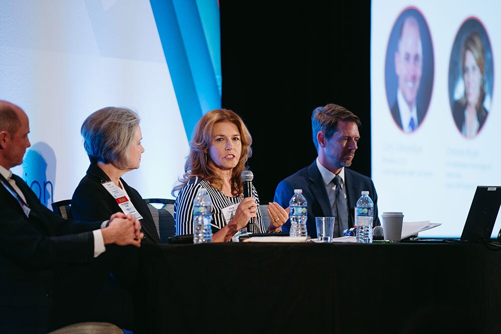Clarity Child Guidance Center's Christine Bryan (center) joined a panel on telling the hospital story - Texas Hospital Association Panel of four at a conference; central woman speaks into a microphone with water bottles on the table nearby.