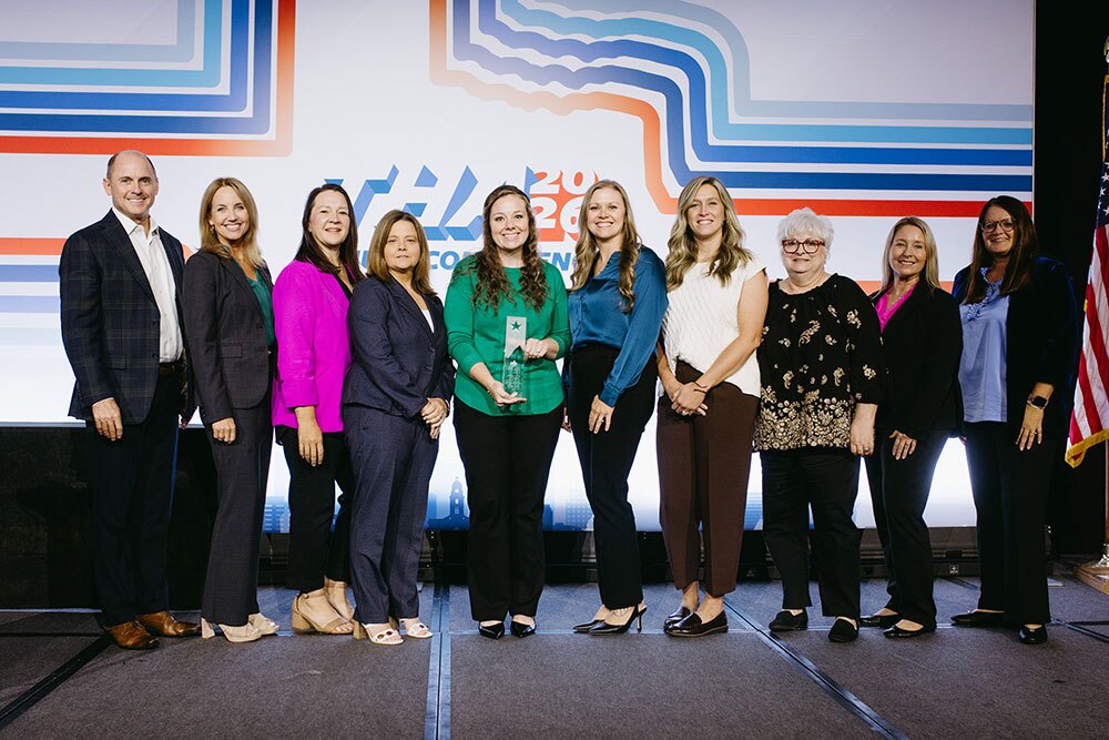 United Regional Health Care System, Wichita Falls accepting the Bill Aston Award for Quality for Non-Research/Non-Teaching Hospital or Health System - Texas Hospital Association Group of professionals on stage posing for a photo at a conference, one person holding an award in the center.
