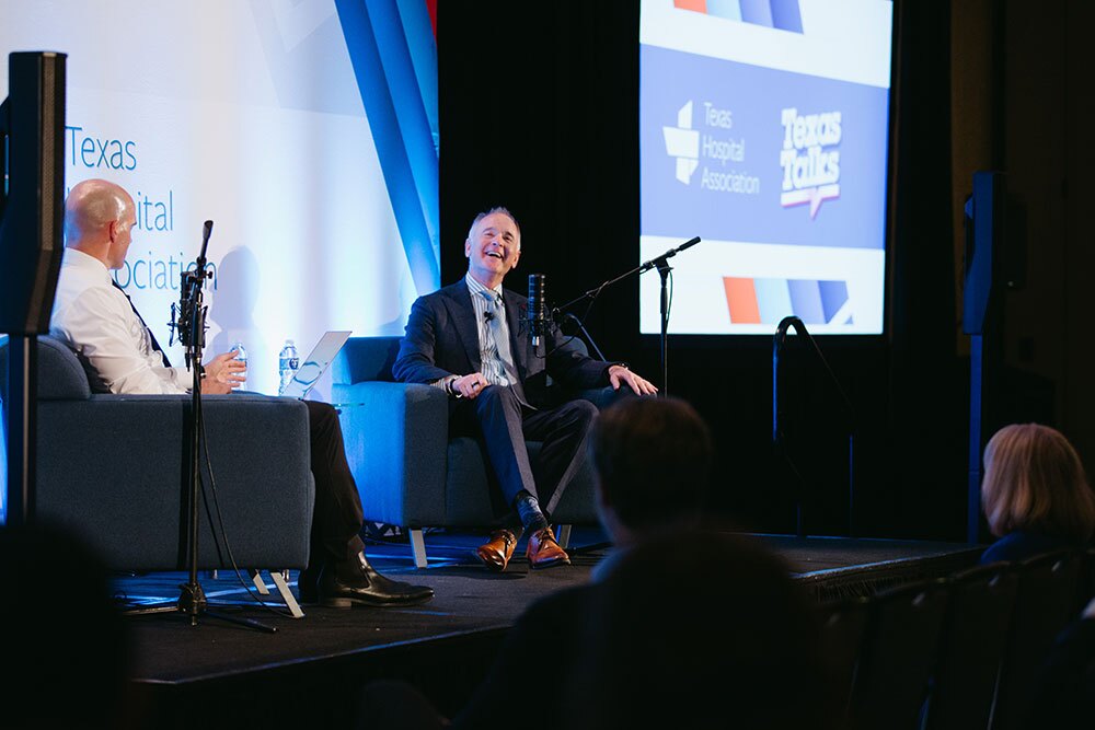 Texas Talks host Bradley Swail (left) interviewed Allen Harrison, president, Medical City Healthcare, HCA Healthcare’s North Texas Division - Texas Hospital Association Two men sit on a stage in armchairs, speaking into microphones during a panel discussion, with screens and banners in the background.