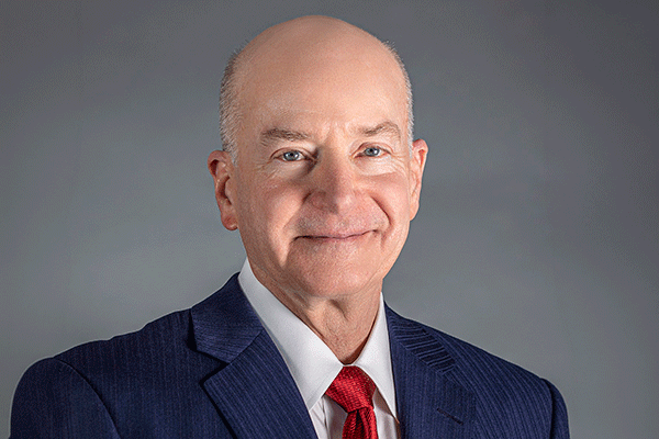 David Callender - Texas Hospital Association Professional headshot of a smiling bald man in a navy suit and red tie against a gray backdrop, looking at the camera.