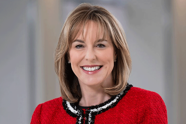 Debbie Sukin - Texas Hospital Association Portrait of a smiling woman with shoulder-length blonde hair wearing a red jacket.