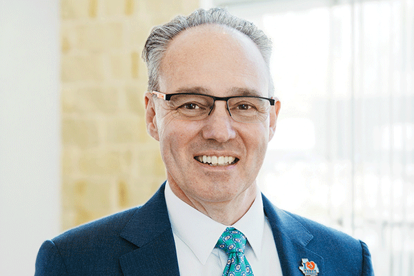 Jim Kendrick - Texas Hospital Association Smiling man in a navy suit and teal tie, wearing glasses—professional headshot in an office setting.