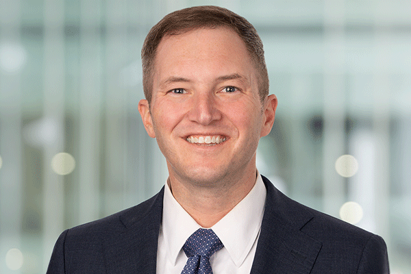 Kyle Armstrong - Texas Hospital Association Professional headshot of a smiling man in a dark suit and blue tie, office backdrop behind him