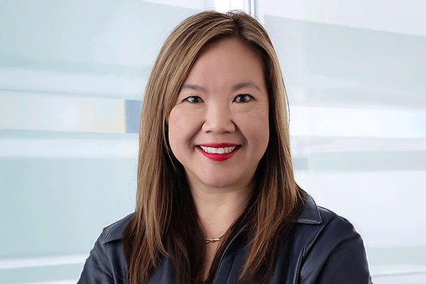 Winjie Tang Miao - Texas Hospital Association Smiling woman with shoulder-length hair in a navy jacket in a bright, modern office environment
