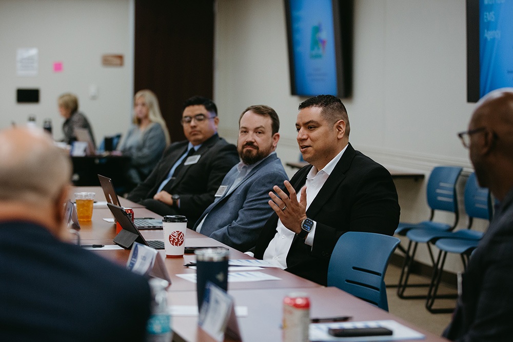 THA Fellows Class of 2026 participating in discussion - Texas Hospital Association Businesspeople seated around a conference table during a panel discussion, with laptops and drinks nearby.