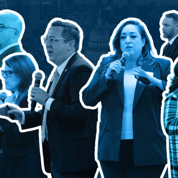 Group of eight professionals holding microphones, speaking on stage at a conference, with white outlines around each figure for emphasis (informative).