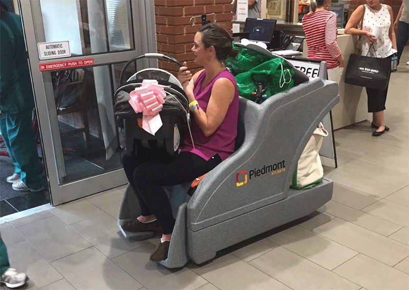 A patient and her belongings riding in a CarryAll cart.