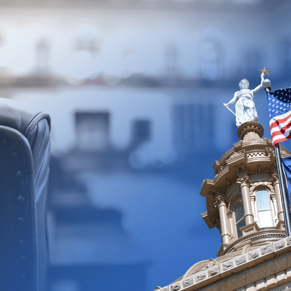Leather chair in the foreground with a government building and waving US and Texas flags in the background.