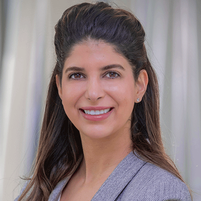 Neyaz Mohammadi - Texas Hospital Association Professional headshot of a smiling woman with long dark hair wearing a gray blazer, neutral background.