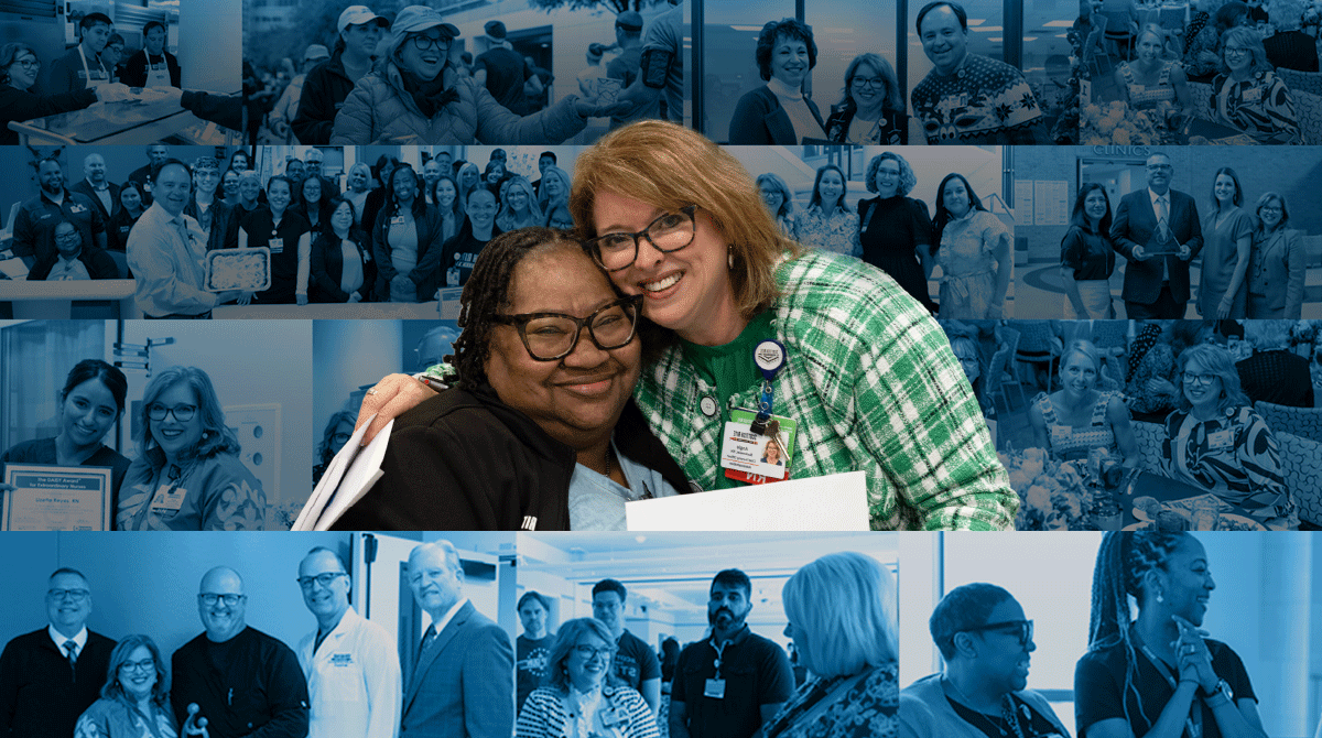 Two smiling women hug in the foreground at a conference, with a blue-tinted collage of team photos behind them.