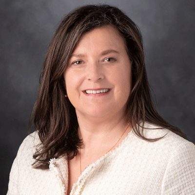 Kim Slusser - Texas Hospital Association Head-and-shoulders portrait of a smiling woman with shoulder-length brown hair, wearing a light beige cardigan.