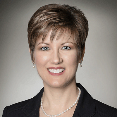 Tracy Payne Martinez - Texas Hospital Association Smiling professional woman with short brown hair, wearing a black blazer and pearl necklace against a neutral backdrop.