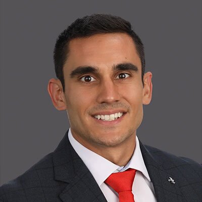 Brandon-Cohen-2026 - Texas Hospital Association Professional headshot of a man in a dark suit with a white shirt and red tie, smiling at the camera.
