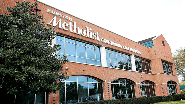 Houston Methodist Continuing Care Hospital - Texas Hospital Association Exterior view of a brick Houston Methodist hospital building with large windows and green shrubbery in front.