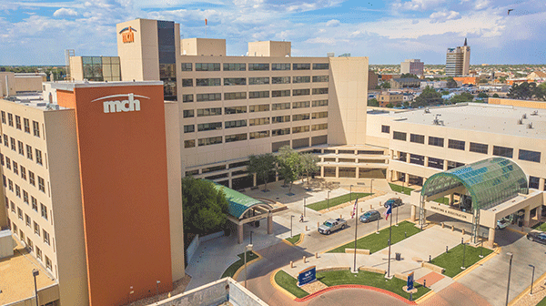 Medical Center Health System - Odessa - Texas Hospital Association Aerial view of a modern hospital campus with a tall red tower labeled'mch' and beige buildings with glass walkways.