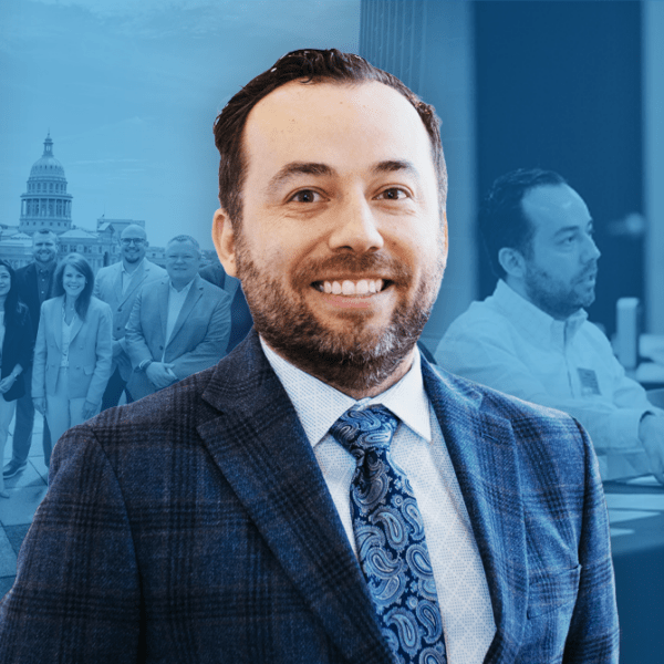 Smiling man in a checkered suit in the foreground with a group of professionals and a government dome in the background, blue-tinted image.